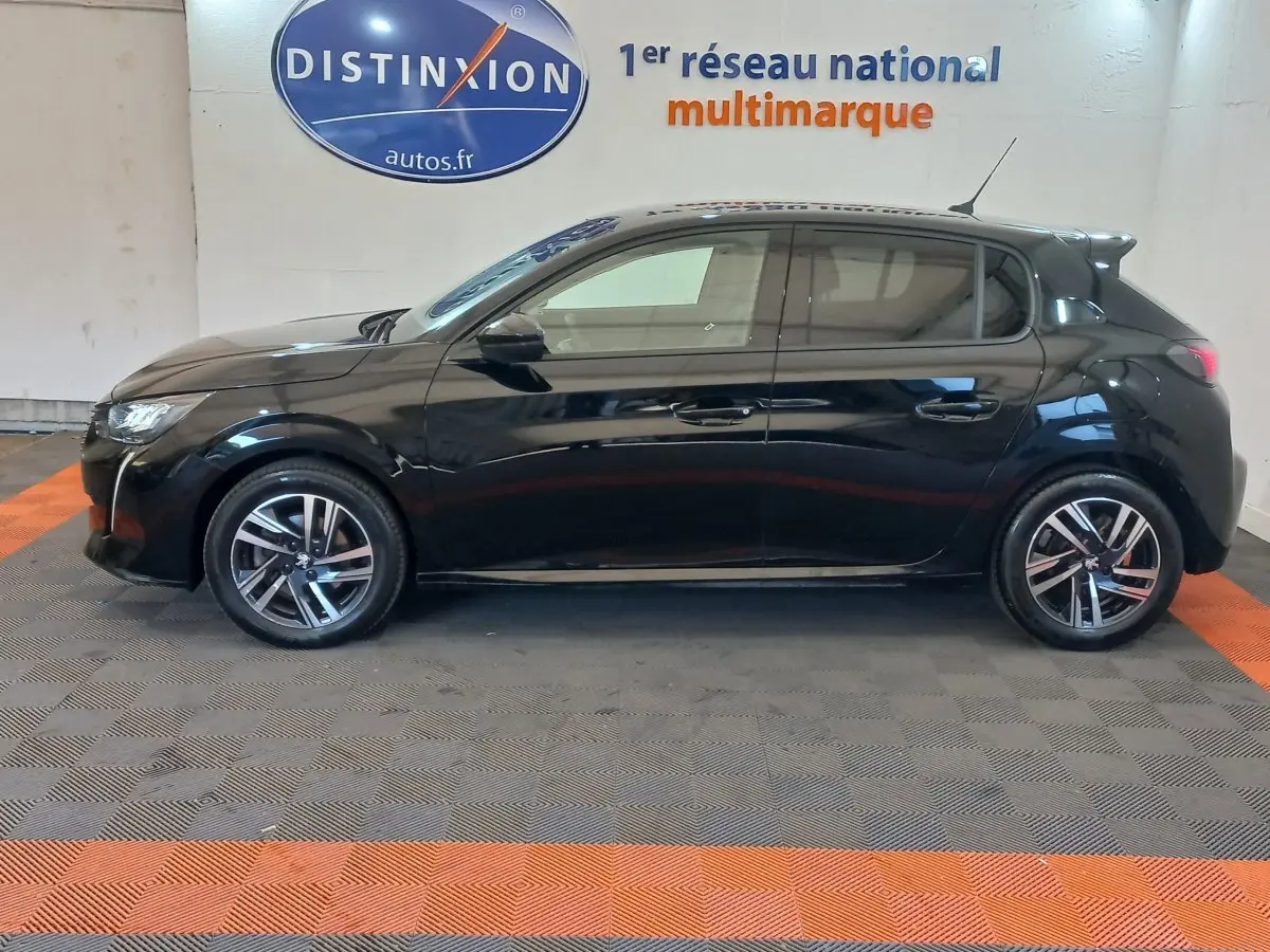 Profil droit d'une Peugeot 208 noire 2022 Allure Pack, avec jantes alliage et vitres teintées en intérieur showroom.