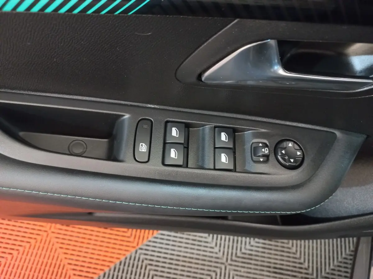 Gros plan sur la commande des vitres et rétroviseurs côté gauche de la porte intérieure noire d’une Peugeot 208 2022.