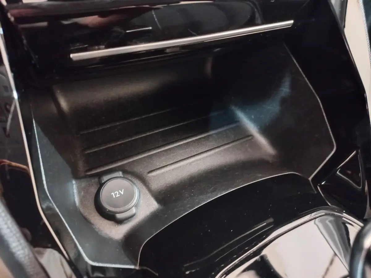Prise 12V en gros plan dans la console centrale noire de la Peugeot 208 PureTech 100 S&S EAT8 Allure Pack 2022.