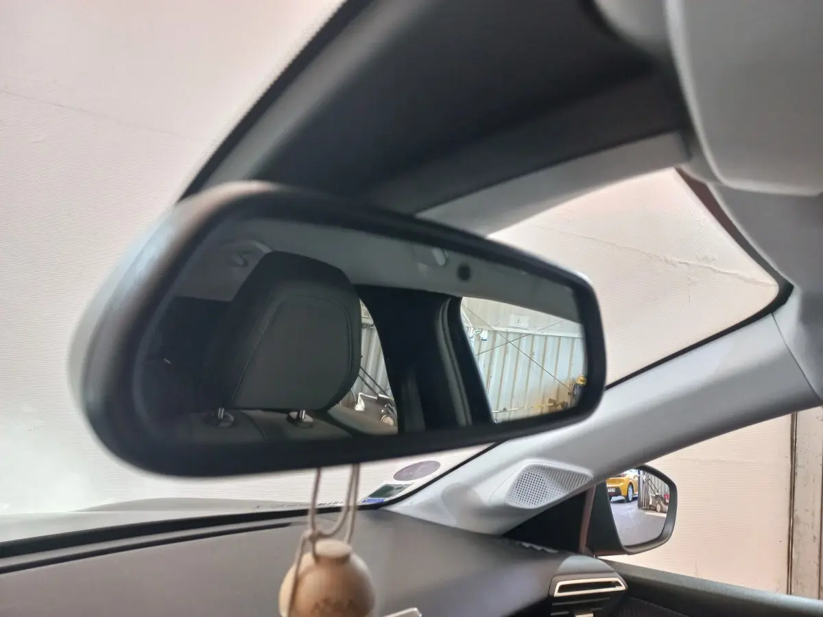 Vue intérieure du rétroviseur central d'une Peugeot 208 noire, avec appui-tête et partie du tableau de bord visibles.