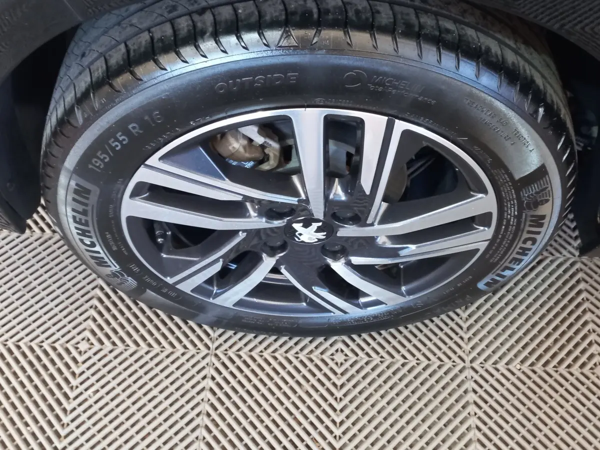 Gros plan sur la jante alliage noire et argentée de la Peugeot 208 PureTech 100, avec pneu Michelin visible.