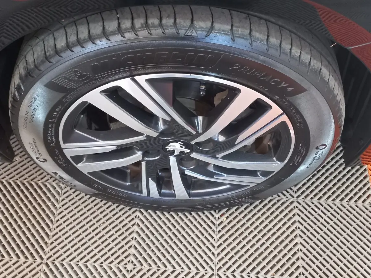 Gros plan sur la jante alliage noire et argentée avec logo Peugeot, montée sur pneu Michelin Primacy 4.