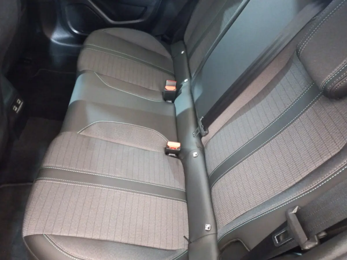 Vue rapprochée de la banquette arrière grise de la Peugeot 208 PureTech 100, montrant les ceintures et les textures du tissu.