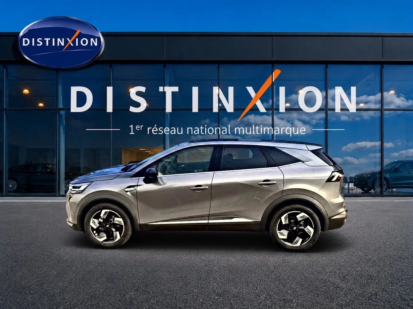 Renault Symbioz gris cassiopée en profil droit devant une vitrine avec logo Distinxion.