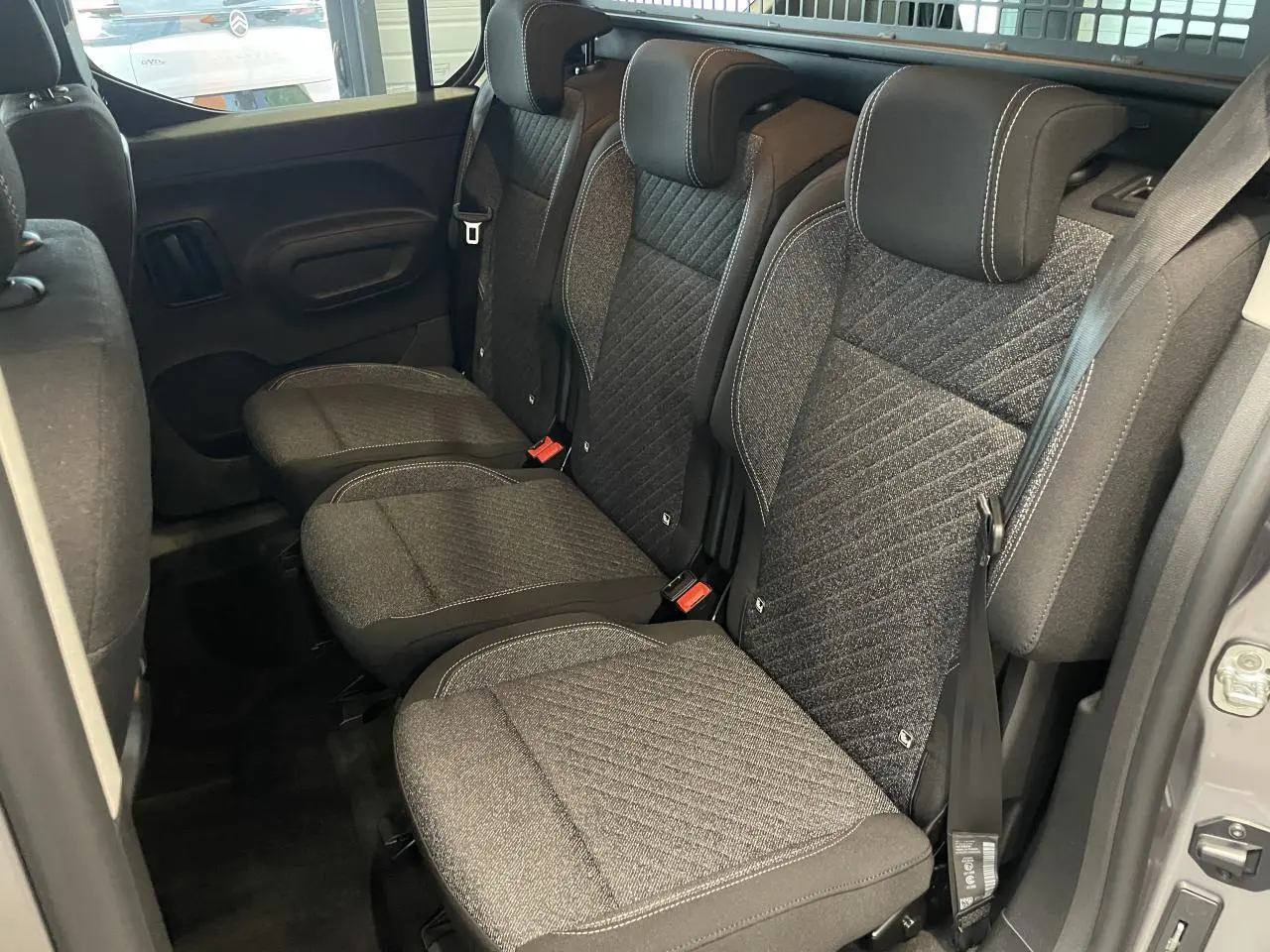 Vue latérale intérieure des sièges arrière en tissu gris du Peugeot Rifter 2026, avec ceintures de sécurité visibles.