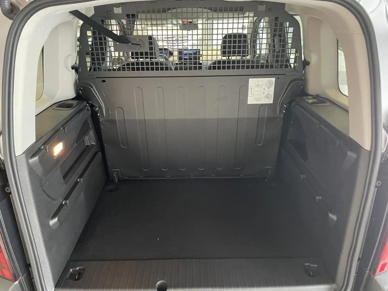 Vue arrière du coffre spacieux du Peugeot Rifter gris Artense avec cloison de séparation métallique noire.