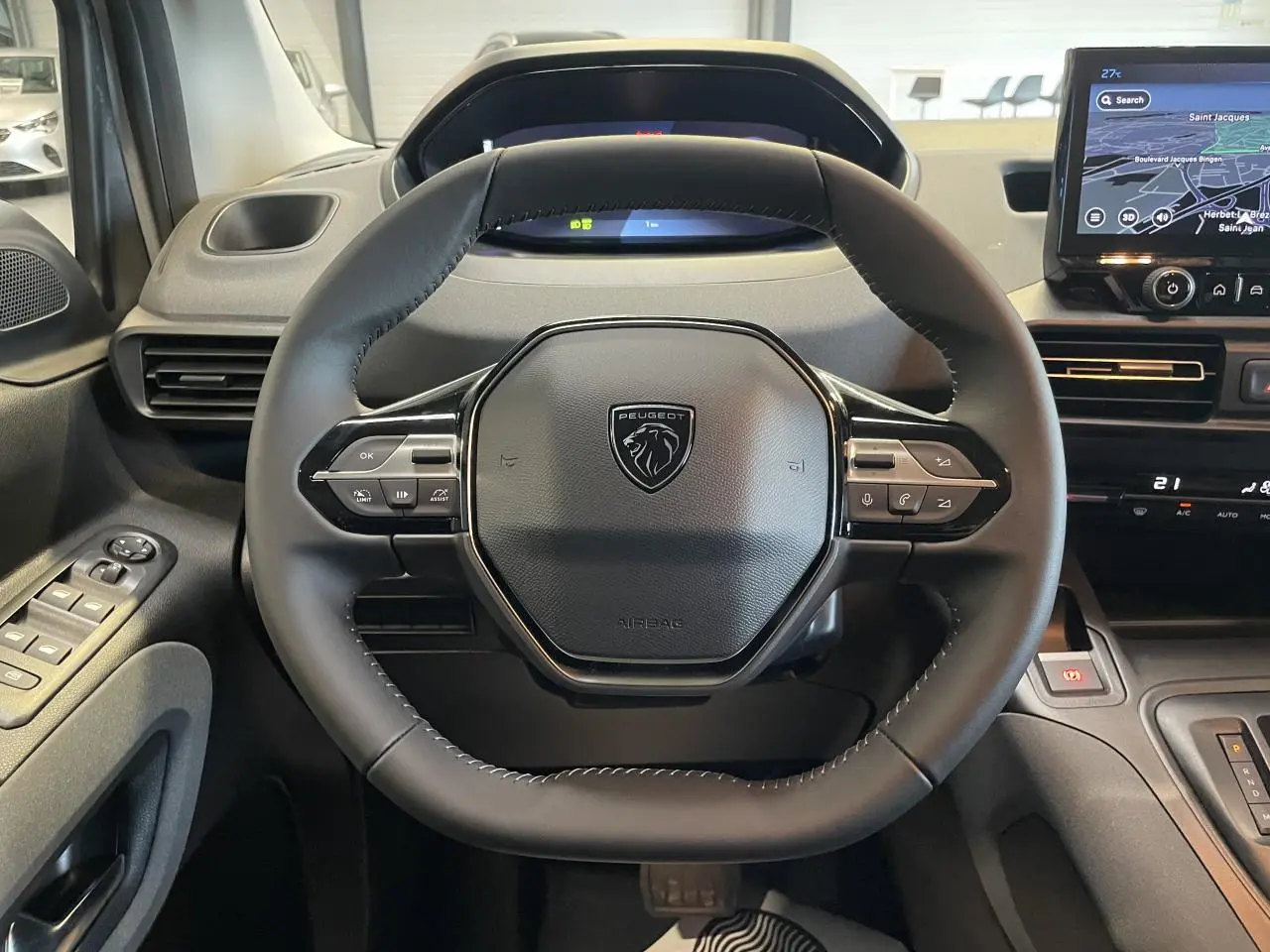 Vue rapprochée du volant cuir multifonction noir du Peugeot Rifter 2026 avec tableau de bord numérique et écran tactile GPS.