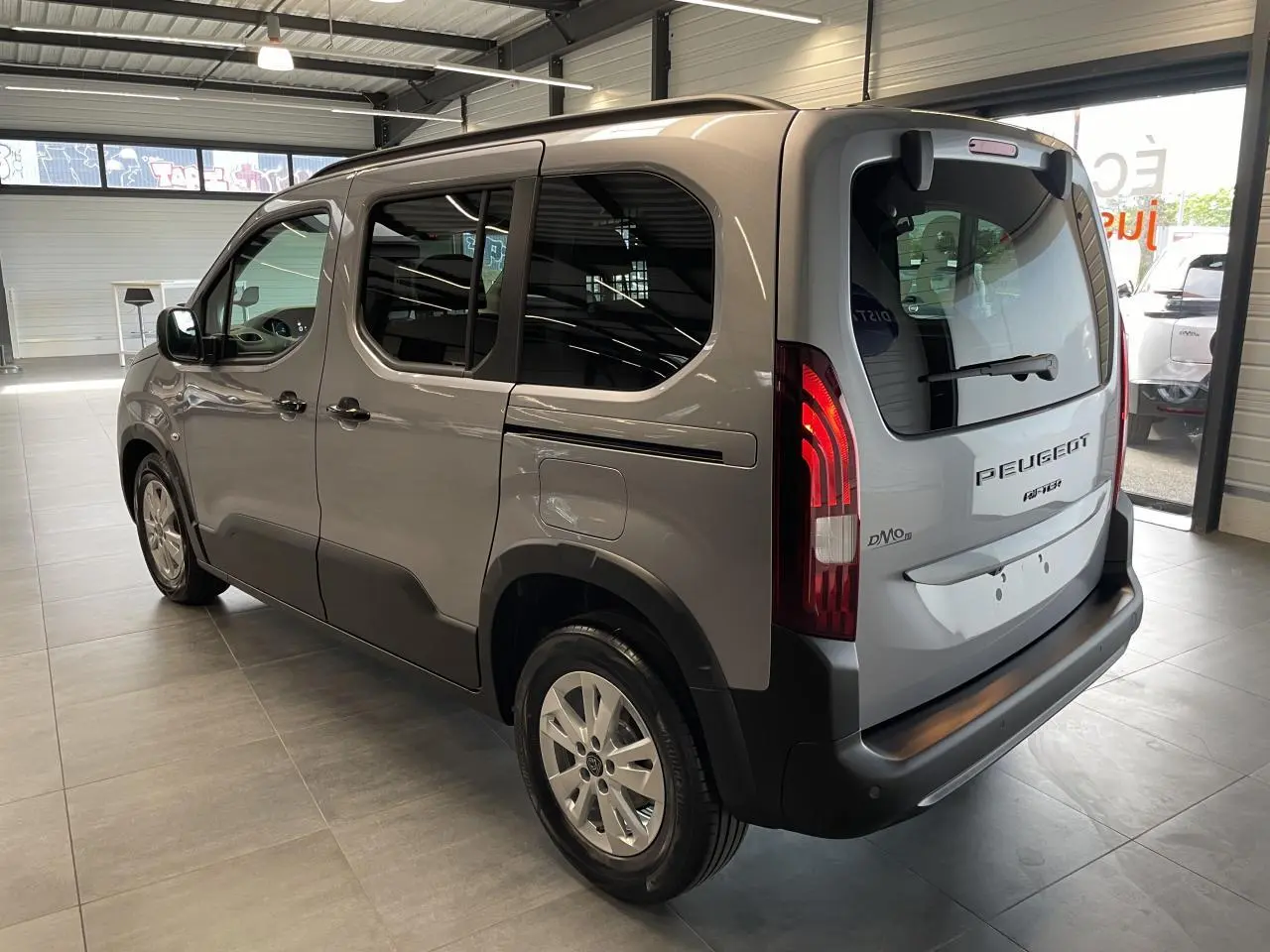 Peugeot Rifter gris Artense vu en 3/4 arrière droit, avec vitres teintées et jantes tôles 16 pouces.