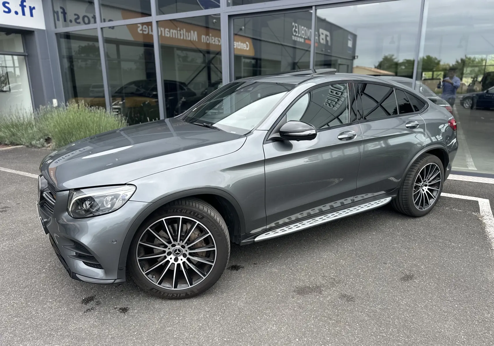 Mercedes GLC Coupé 250 D gris foncé vu de côté gauche 3/4 avant, avec jantes alliage et marchepieds métalliques.