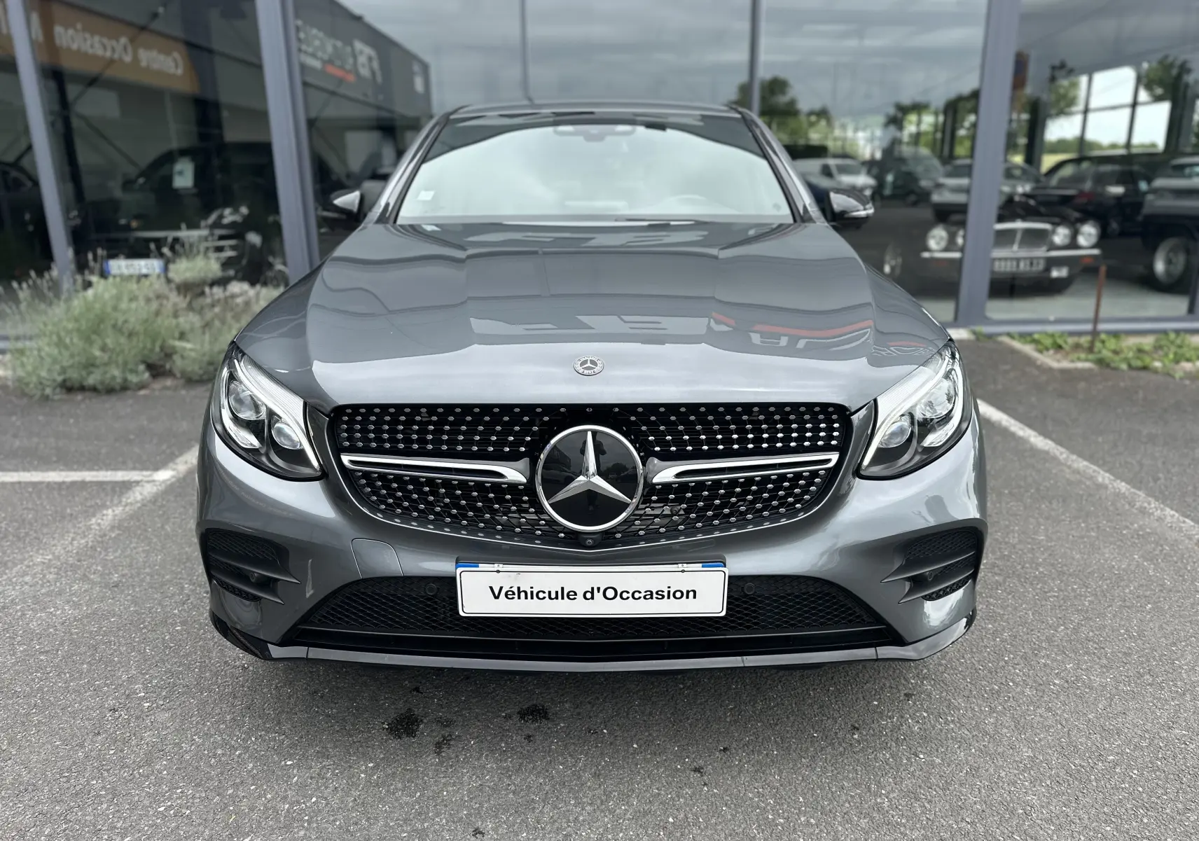 Vue frontale d'un Mercedes GLC Coupé 250 D Fascination gris foncé avec calandre diamant et logo central visible.