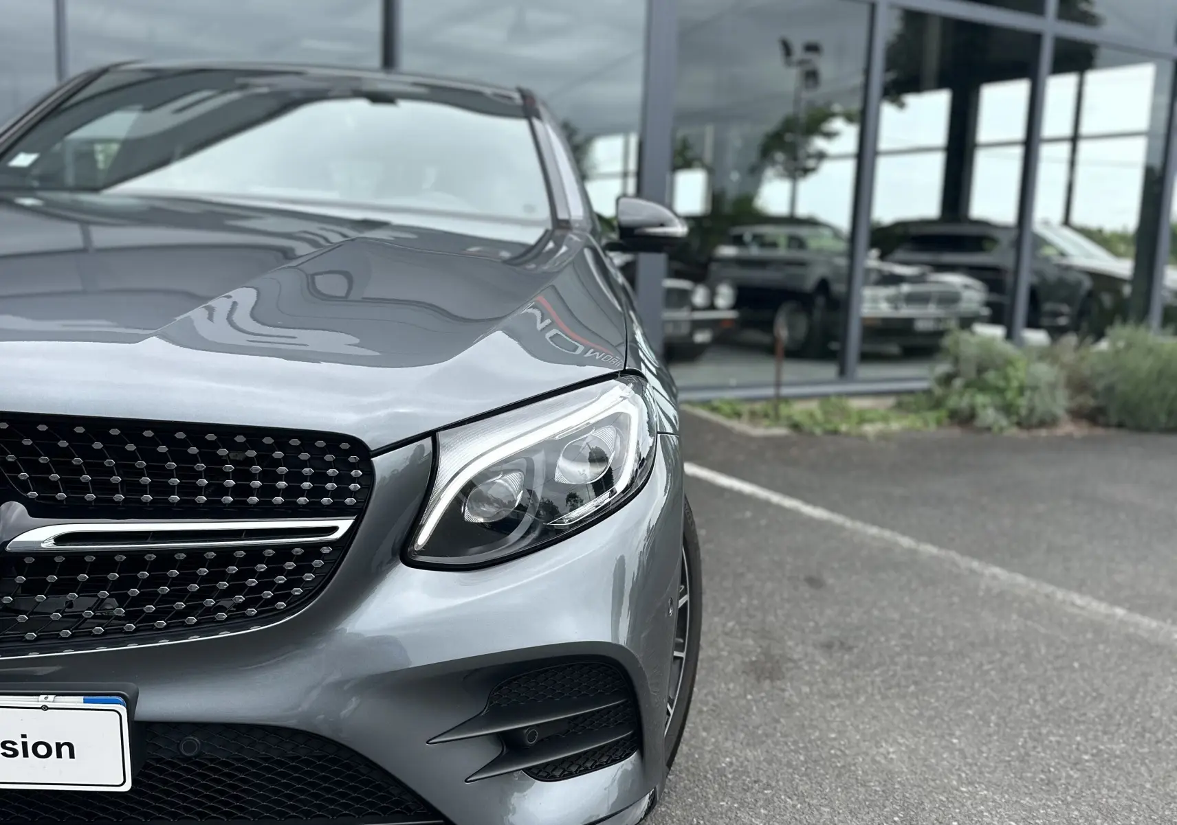 Vue 3/4 avant droit d'un Mercedes GLC Coupé 250 D Fascination gris foncé, avec calandre étoilée et phares LED visibles.