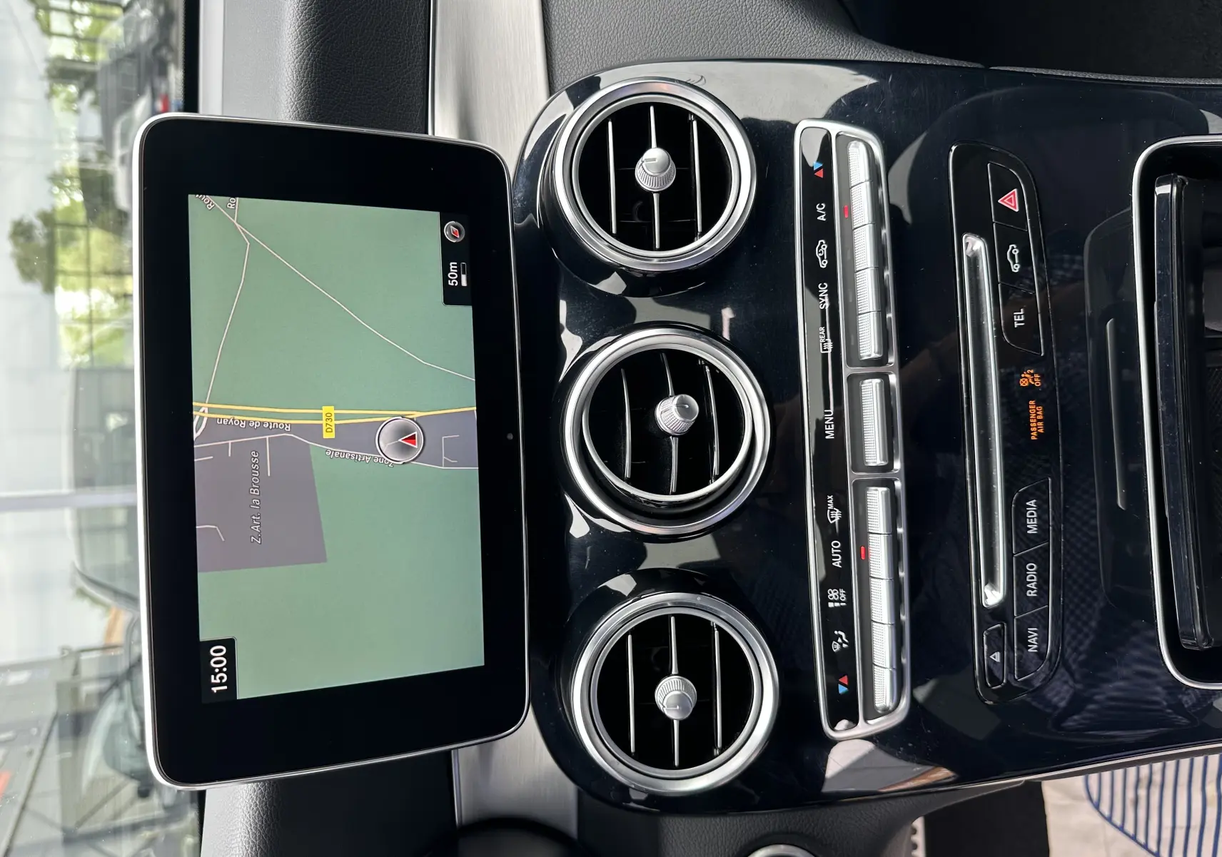 Vue rapprochée du tableau de bord noir brillant du Mercedes GLC Coupé gris foncé avec écran GPS et aérateurs ronds chrome.