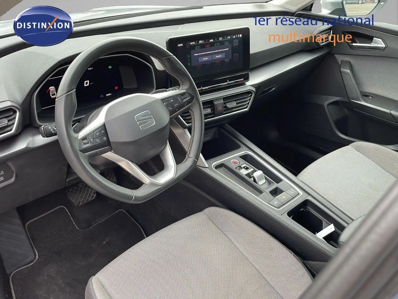 Vue intérieure côté conducteur du SEAT LEON ST 2023 gris urbain, tableau de bord moderne avec écran tactile central.