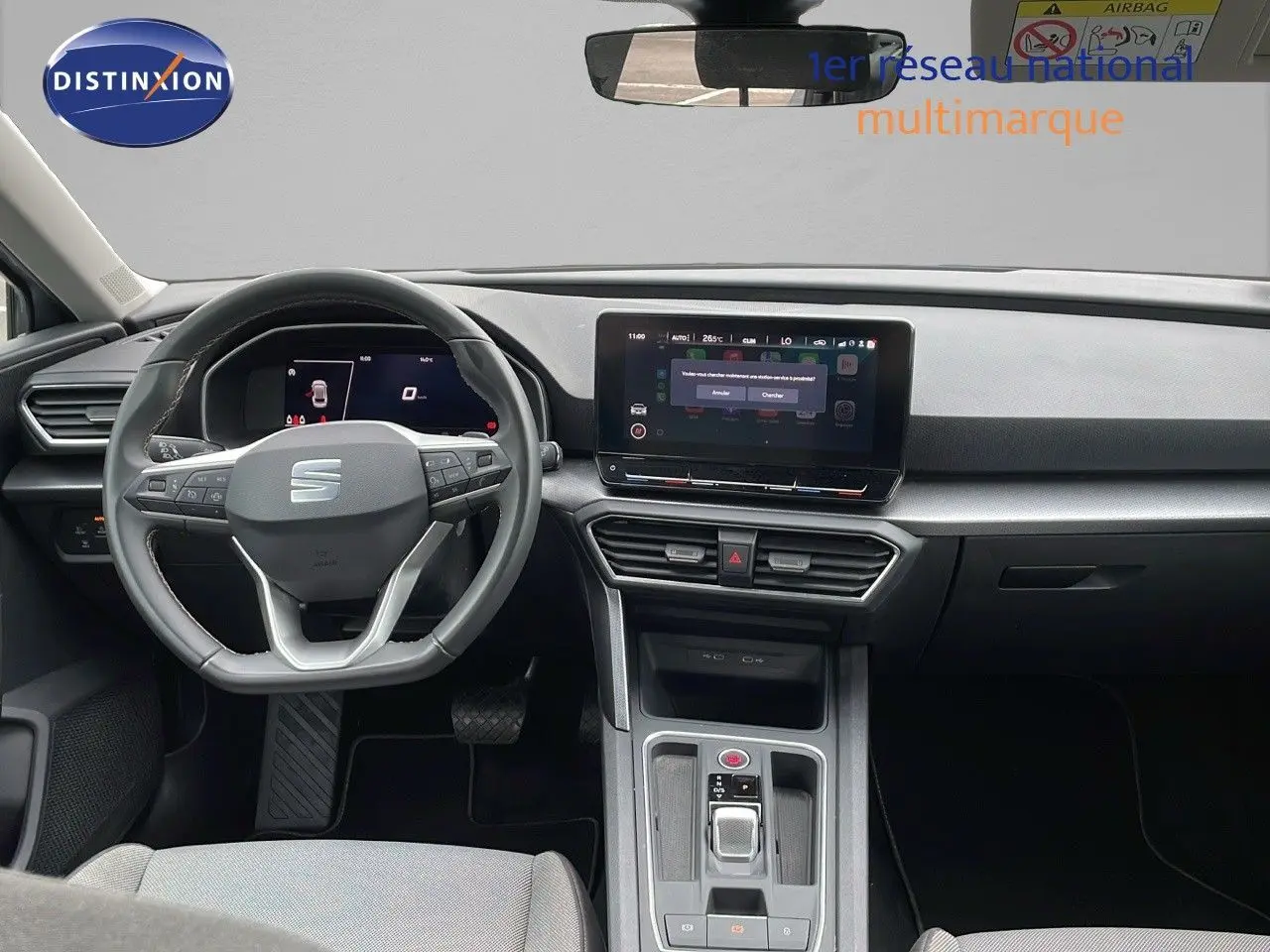 Intérieur moderne gris et noir de la SEAT LEON ST 2023, vue frontale sur le tableau de bord et volant multifonction.