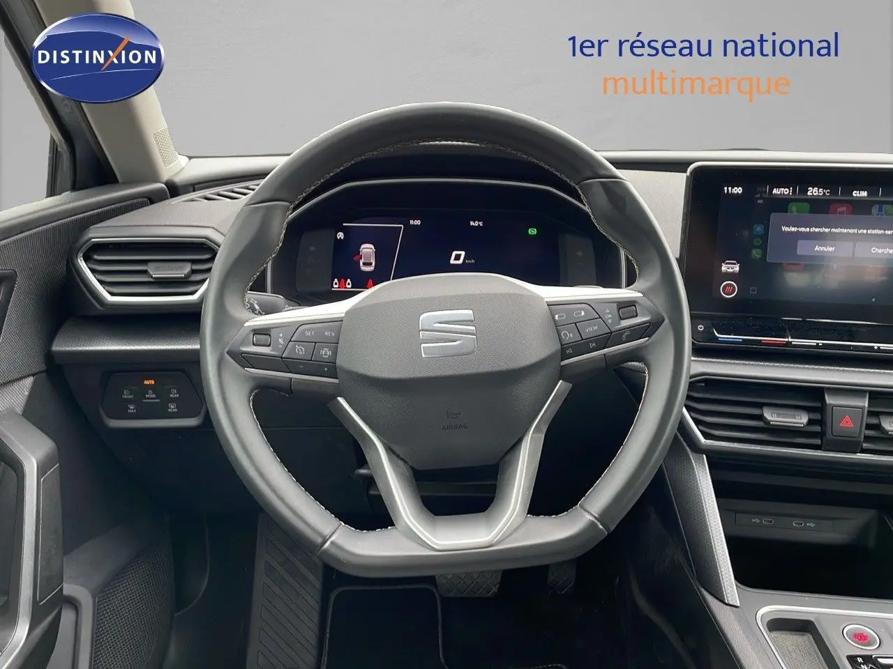 Vue rapprochée du volant et du tableau de bord numérique d'une SEAT LEON ST gris urbain 2023 avec écran tactile central.