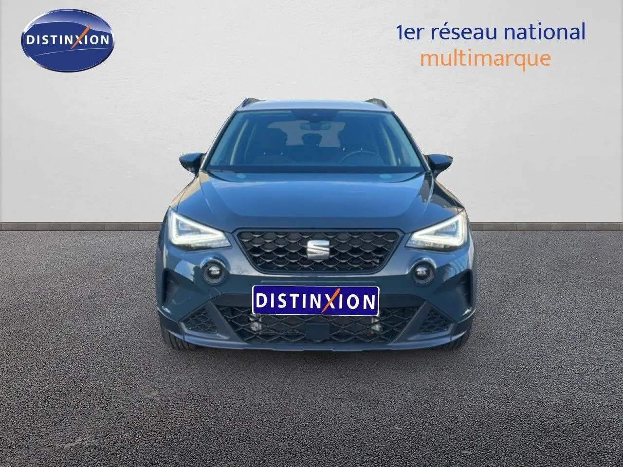 Vue avant d'une SEAT Arona gris magnétique métal, avec calandre noire et phares LED allumés.