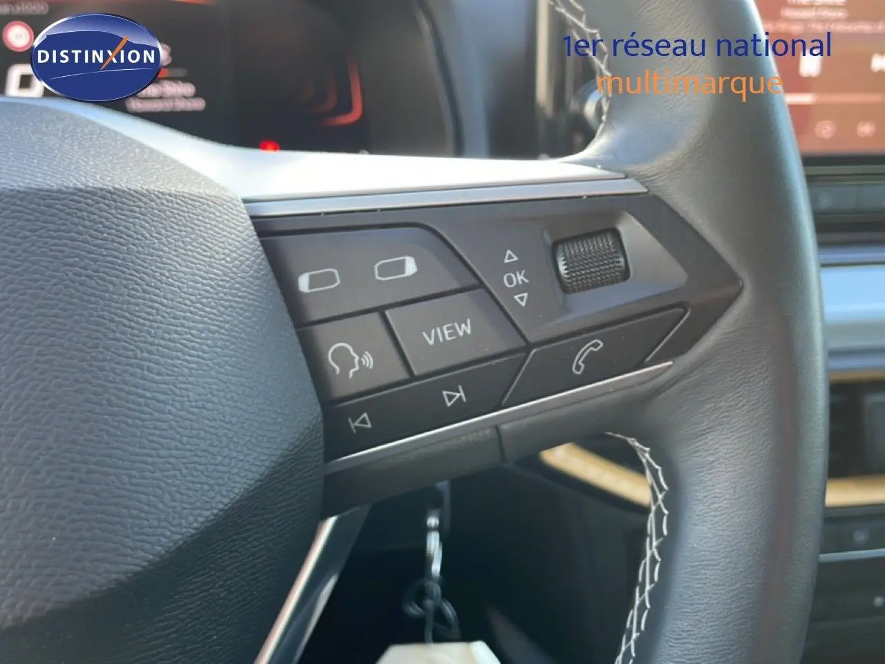 Gros plan sur le volant cuir avec commandes multifonctions du SEAT Arona gris magnétique, intérieur noir visible en arrière-plan.