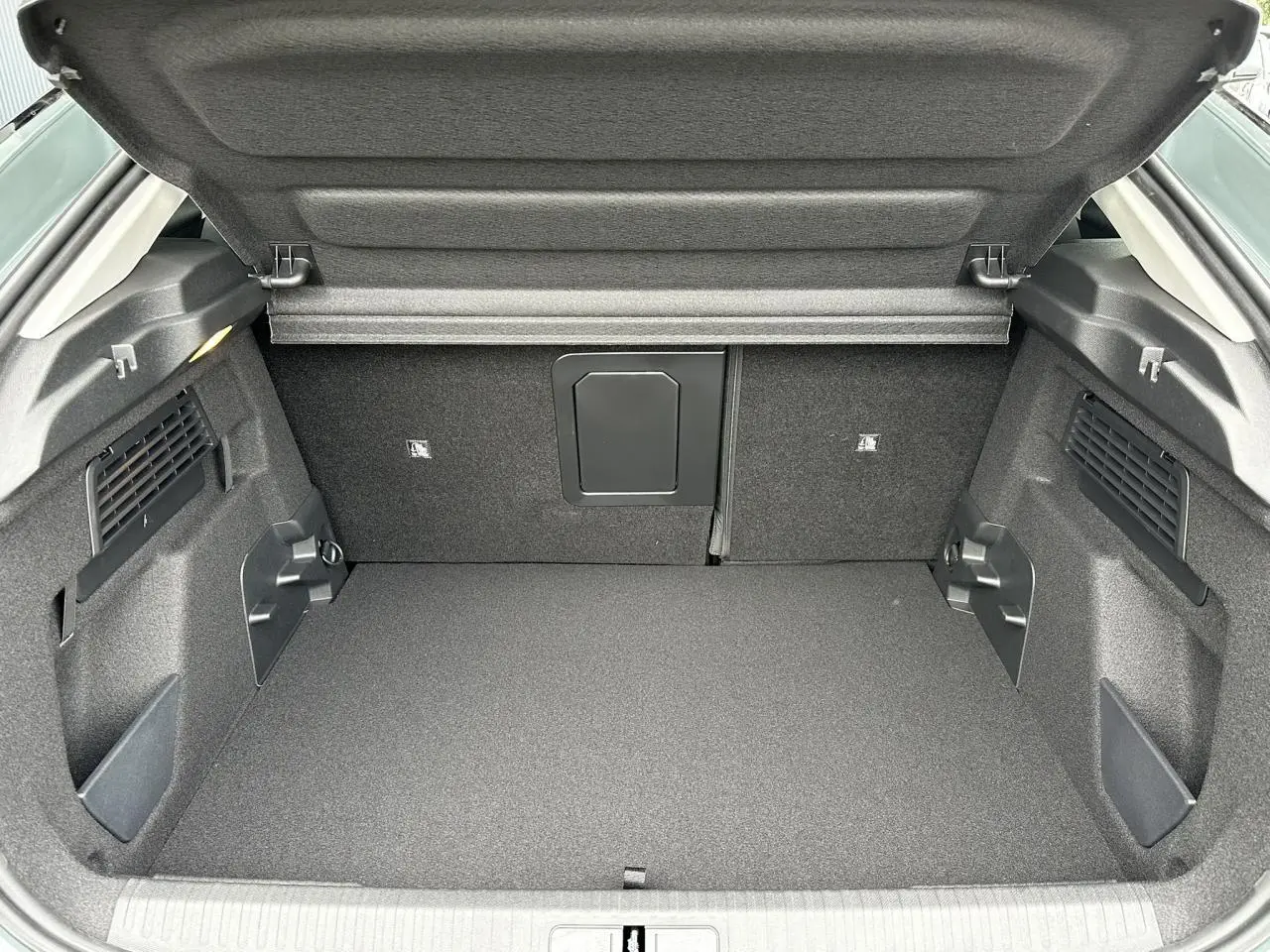 Coffre ouvert vu de l’arrière d’une Citroën C4 Manhattan Green avec intérieur noir et compartiments latéraux.