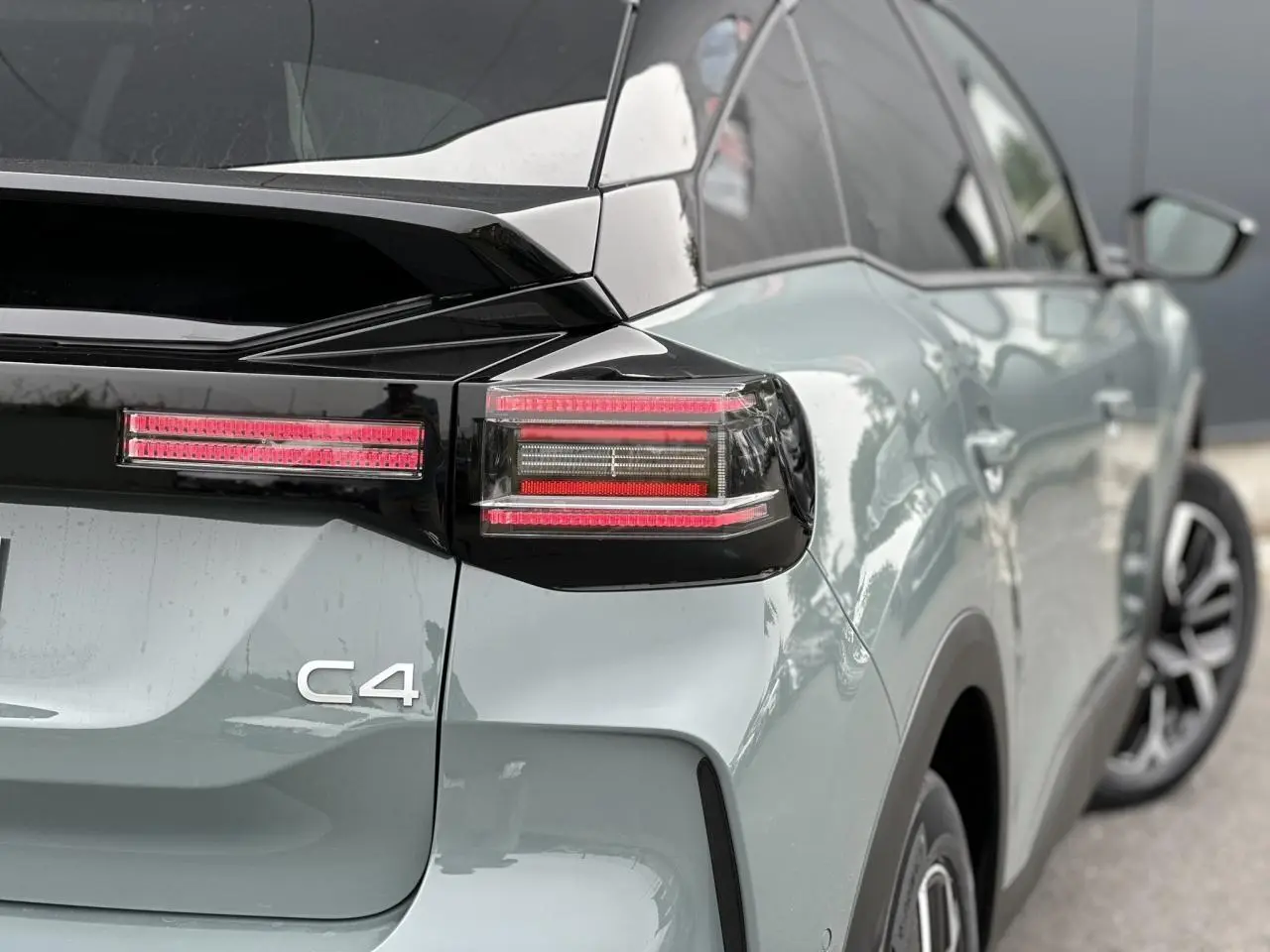 Vue 3/4 arrière droite d'une Citroën C4 Manhattan Green avec toit noir et feux arrière LED distinctifs.