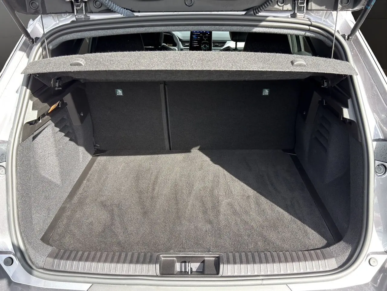 Coffre ouvert vu de l'arrière d'une Renault Symbioz gris clair, montrant un espace de chargement propre et spacieux.