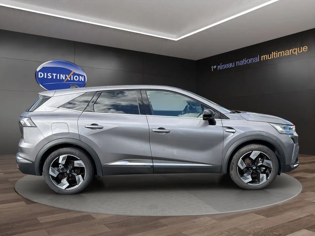 Profil droit du Renault SYMBIOZ gris clair 2025 avec jantes noires et détails chromés, présenté en intérieur showroom.