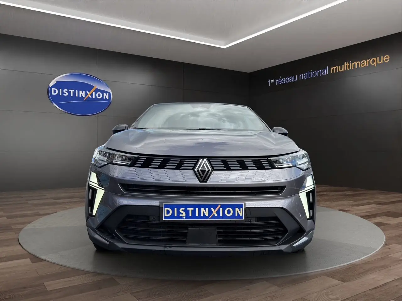 Vue avant d'une Renault Symbioz gris clair avec éclairage LED distinctif, présentée en showroom Distinxion.