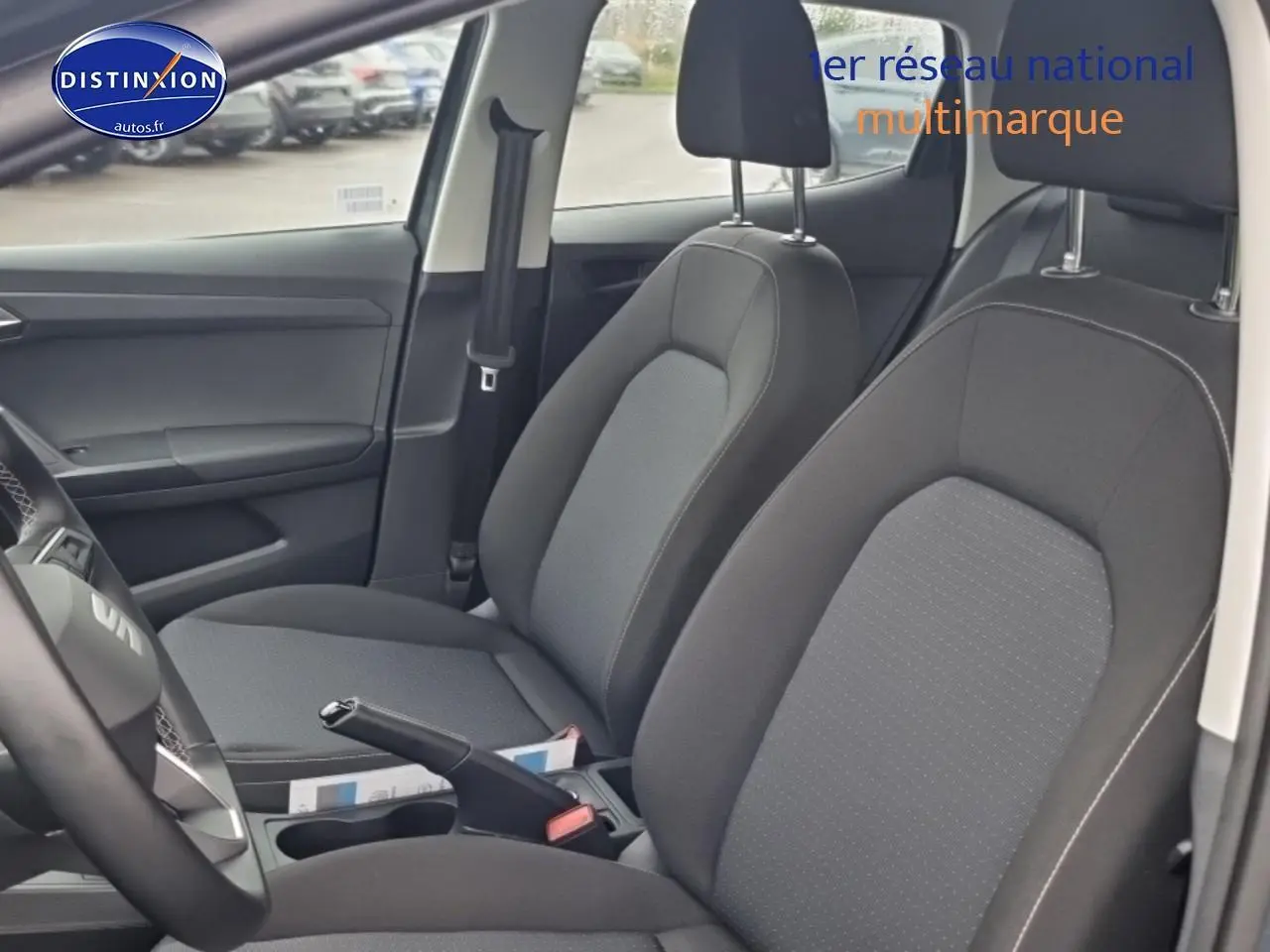 Vue intérieure côté conducteur de la SEAT Ibiza gris 2025, sièges tissu gris et volant multifonction cuir.