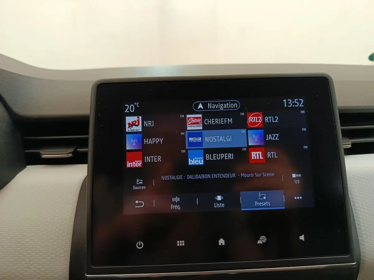 Écran tactile central de la Renault Clio blanc 2023 affichant les stations radio et la navigation.