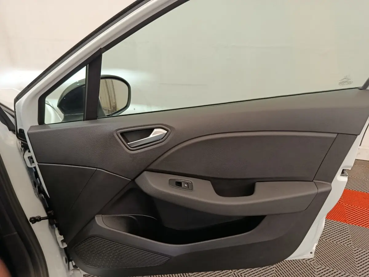 Vue intérieure de la porte avant gauche blanche d'une Renault Clio 2023, avec poignée argentée et panneau noir.