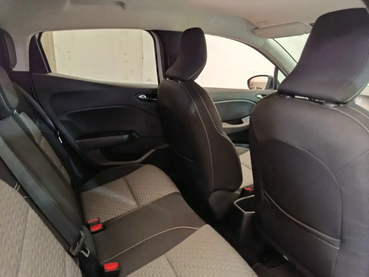 Vue intérieure côté gauche montrant la banquette arrière et les sièges avant noirs de la Renault Clio blanche.