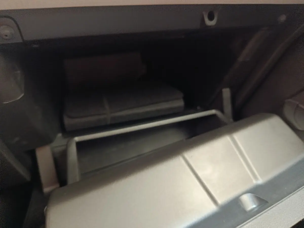 Gant de boîte à gants ouvert en plastique gris à l'intérieur d'une Renault Clio blanche, vue intérieure côté passager.