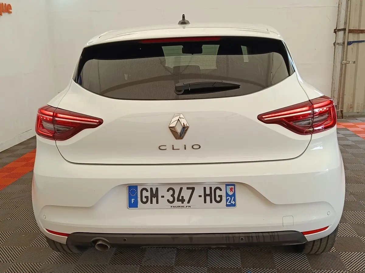 Vue arrière d'une Renault Clio blanche 2023 avec feux LED allumés et plaque d'immatriculation française visible.