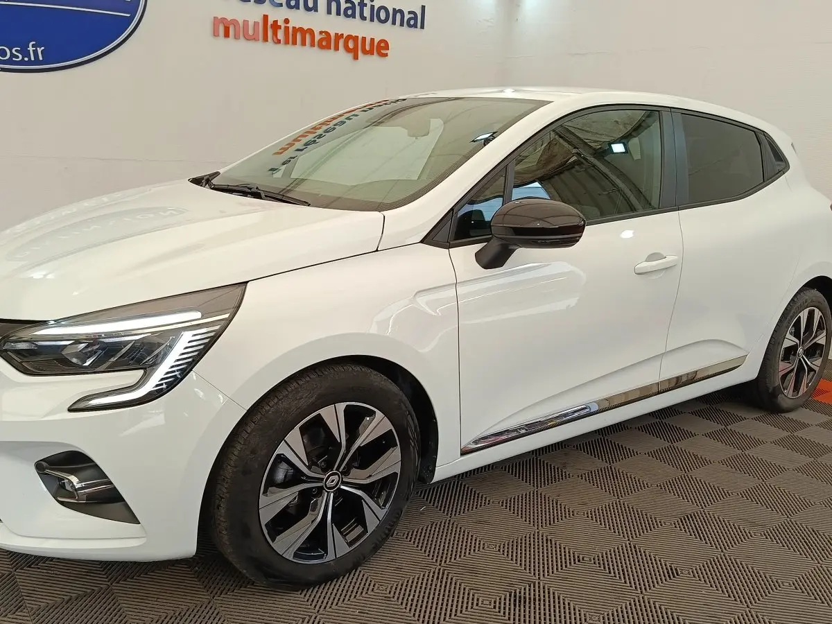 Vue 3/4 avant droit d'une Renault Clio blanche Evolution TCe 100 GPL avec jantes noires et rétroviseurs noirs.