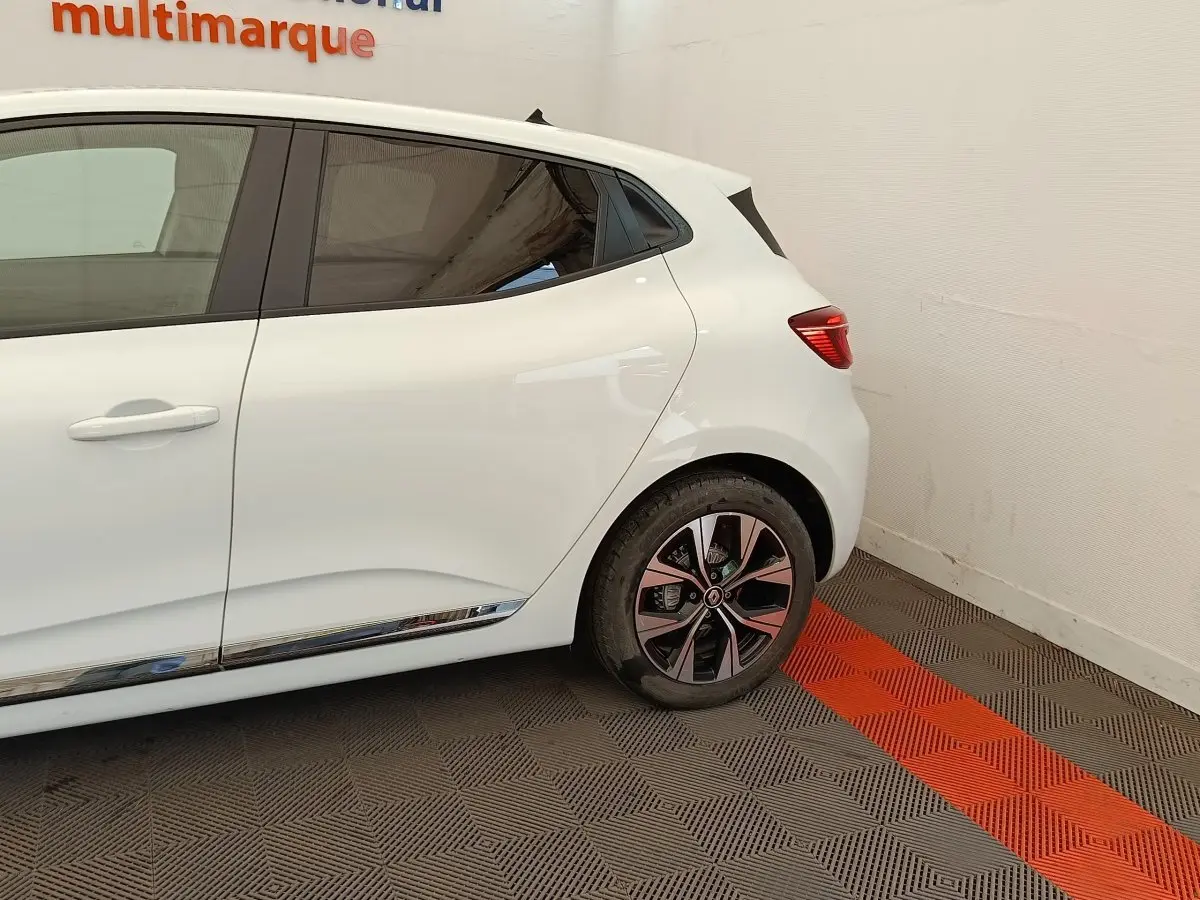 Vue latérale droite sur l'arrière d'une Renault Clio blanche 2023 avec jante alliage et poignée de porte intégrée.
