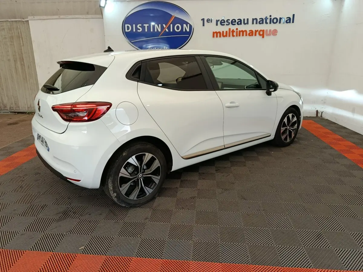 Renault Clio Evolution TCe 100 GPL blanc vue 3/4 arrière côté droit, avec jantes noires et toit spoiler.