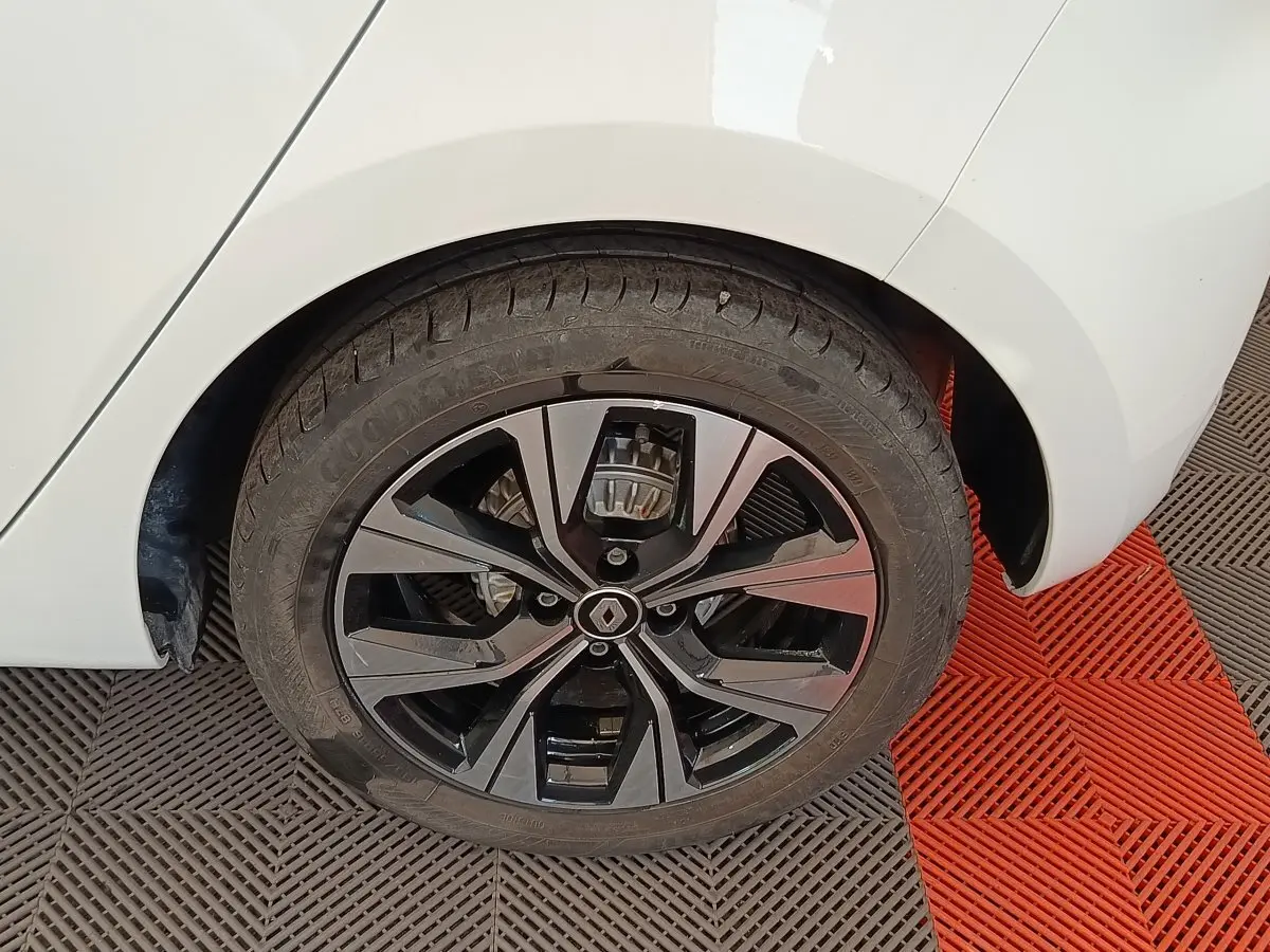 Gros plan sur la roue arrière droite d'une Renault Clio blanche avec jante alliage noire et argentée.