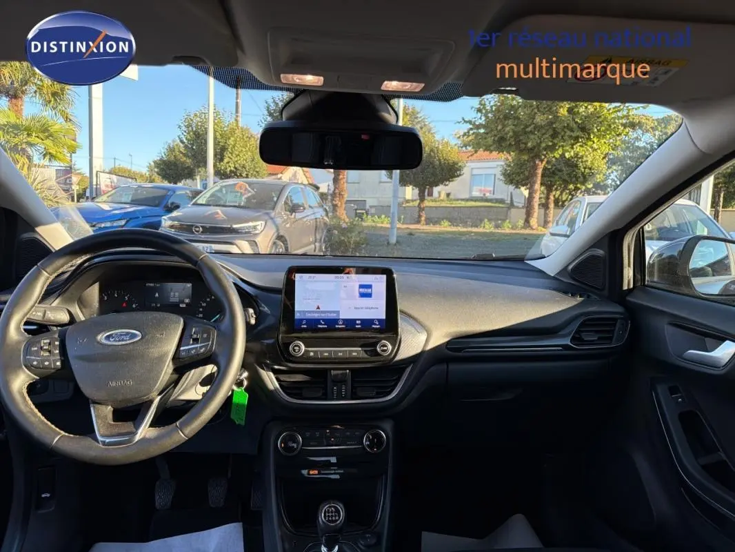 Vue intérieure avant du Ford Puma noir 2023, tableau de bord avec écran tactile et volant multifonction.