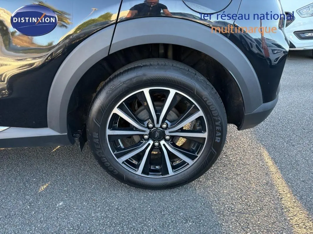 Gros plan sur la roue arrière droite noire du Ford Puma 2023 avec jante 17 pouces bicolore et logo Ford visible.