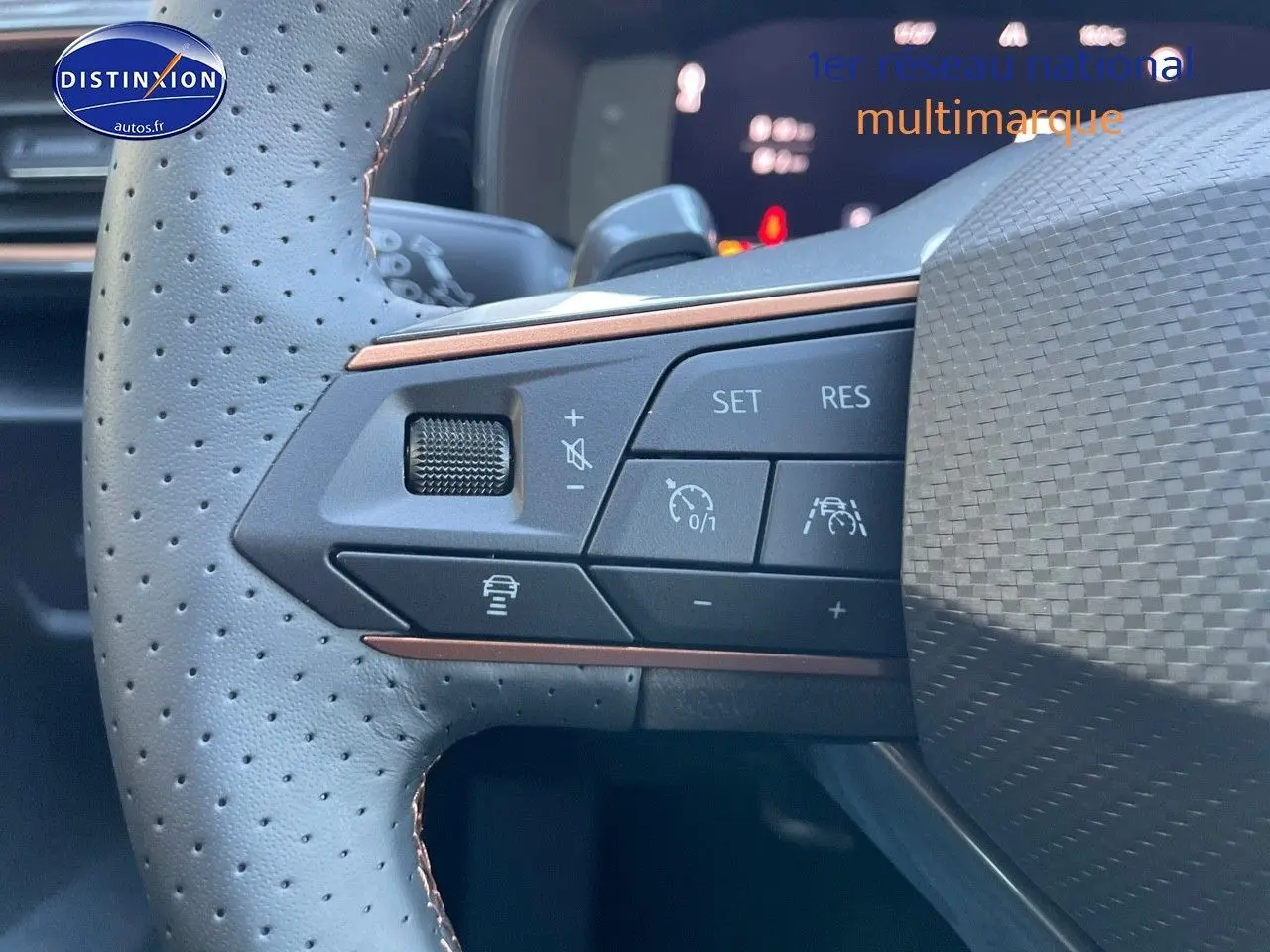 Gros plan sur les commandes du volant en cuir perforé gris d'une CUPRA Formentor 1.4 E-HYBRID 2024, avec boutons de régulateur.