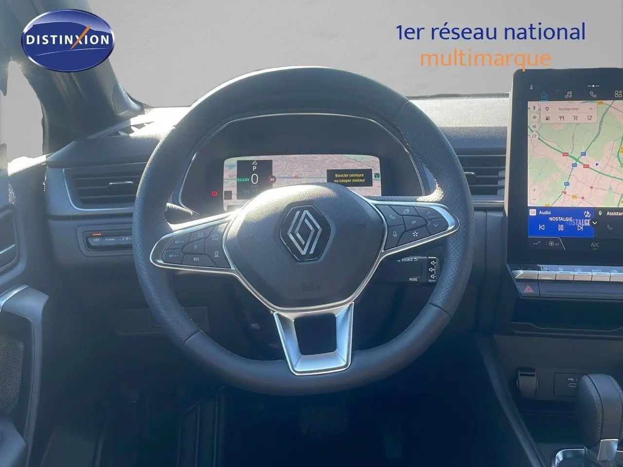 Vue intérieure centrée sur le volant Renault noir avec tableau de bord numérique et écran tactile multimédia à droite