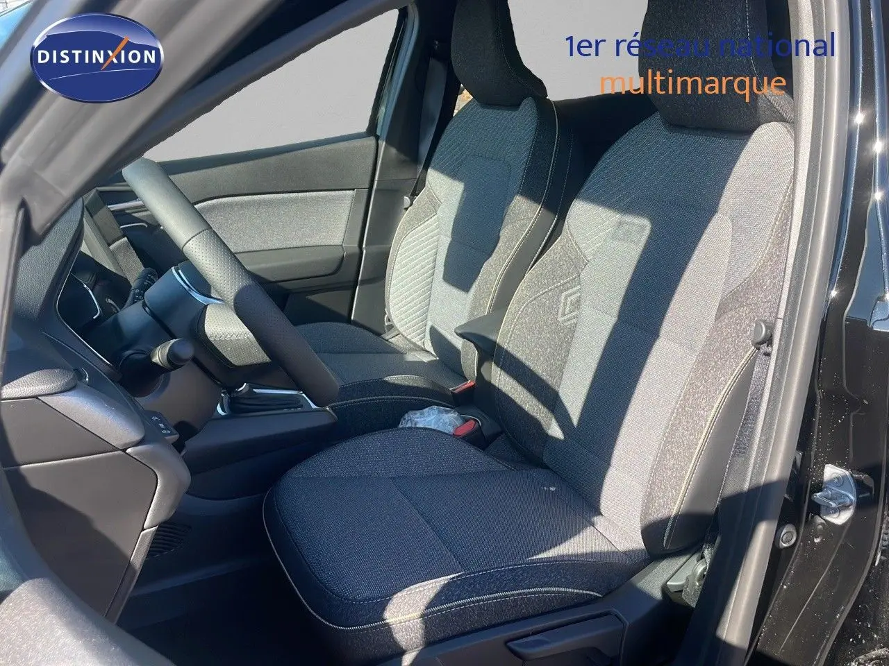 Vue intérieure côté conducteur du Renault Captur E-Tech hybride 2025 avec sièges tissu noir et gris et volant visible.