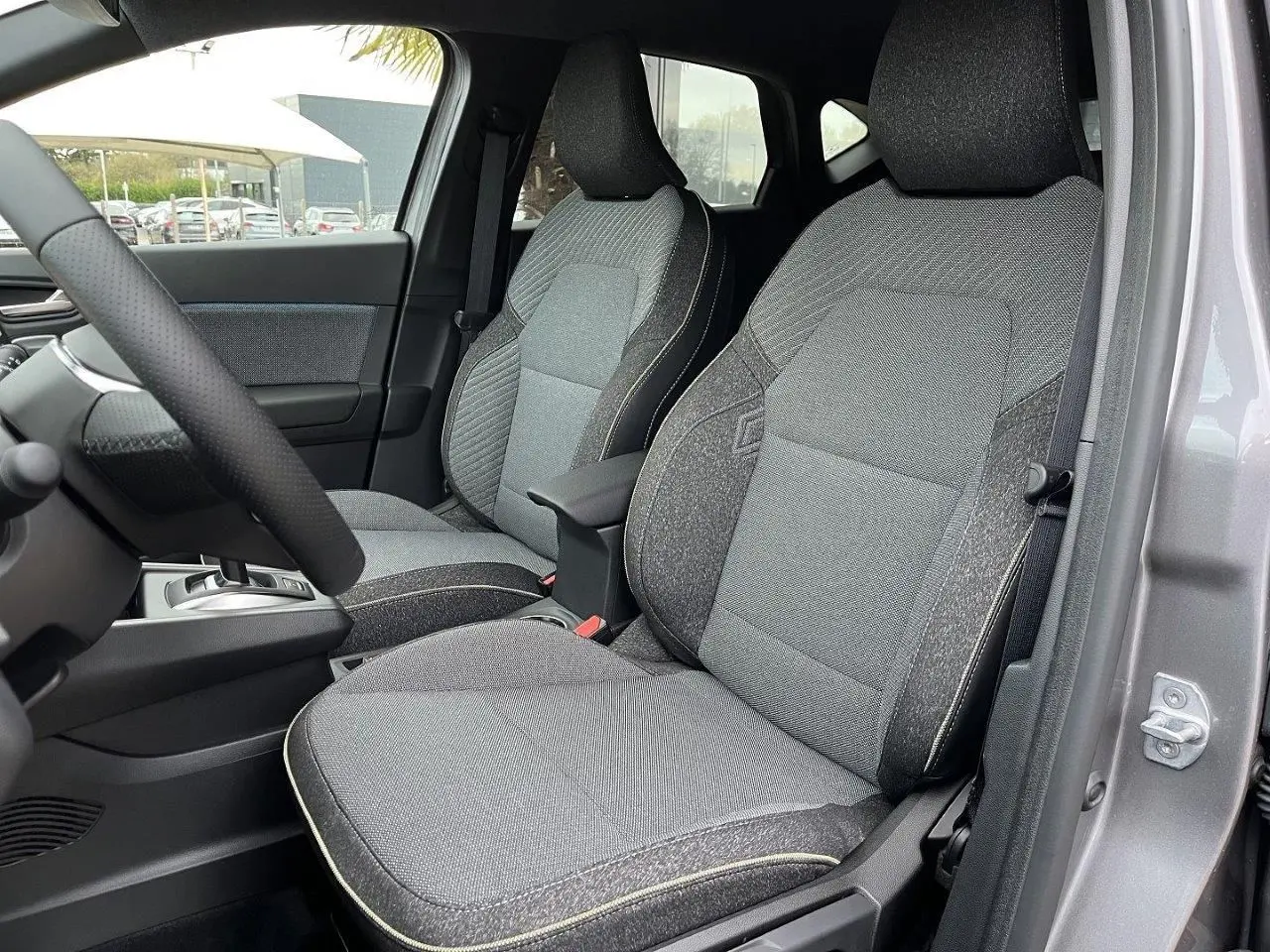 Vue intérieure côté gauche montrant les sièges avant gris du Renault Captur 2025 en version hybride full hybrid.