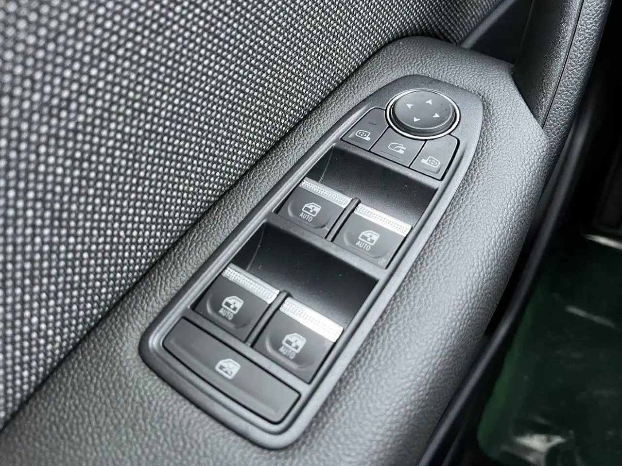 Gros plan sur les commandes de lève-vitres et rétroviseurs côté gauche d’un Renault Captur gris Cassiopée 2025.