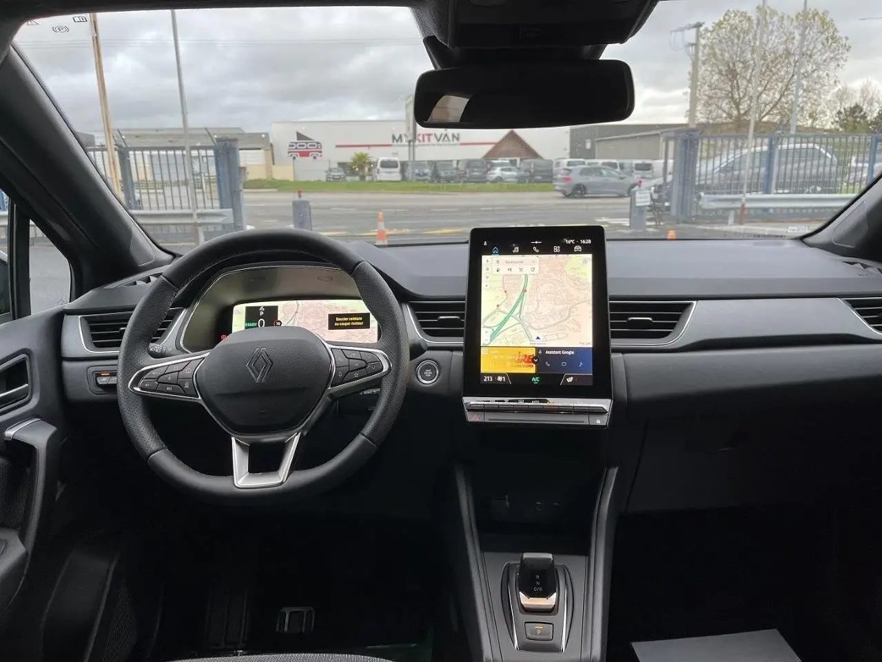 Vue intérieure frontale du tableau de bord du Renault Captur gris Cassiopée 2025 avec écran tactile vertical et volant multifonction.