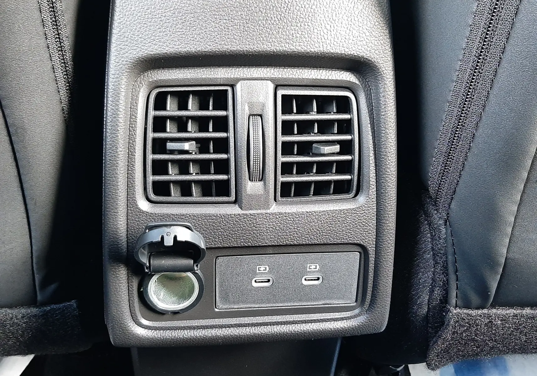 Détail de la console arrière avec bouches d'aération, prise 12V et deux ports USB-C dans un Renault Captur gris Cassiopée.