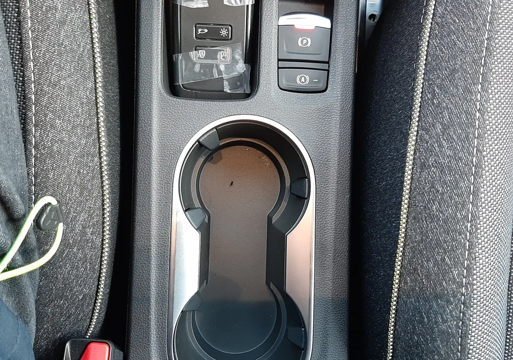 Vue plongeante sur la console centrale du Renault Captur gris Cassiopée, avec porte-gobelets et commandes électroniques.