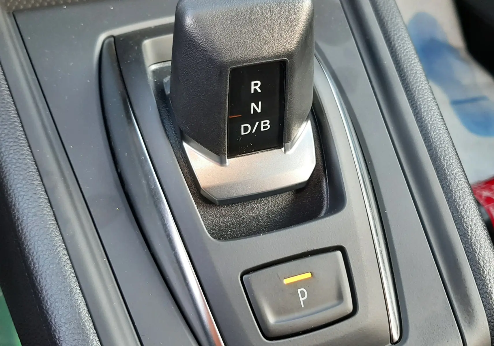 Gros plan sur le levier de vitesses automatique noir et argenté du Renault Captur gris Cassiopée, avec bouton de parking éclairé.