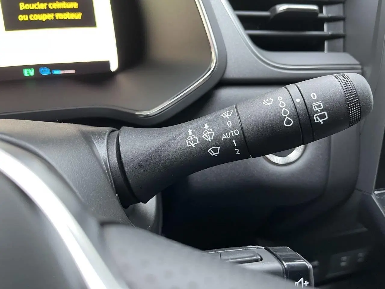 Gros plan sur la commande d’essuie-glace à droite du volant dans l’habitacle sombre du Renault Captur gris Cassiopée 2025.