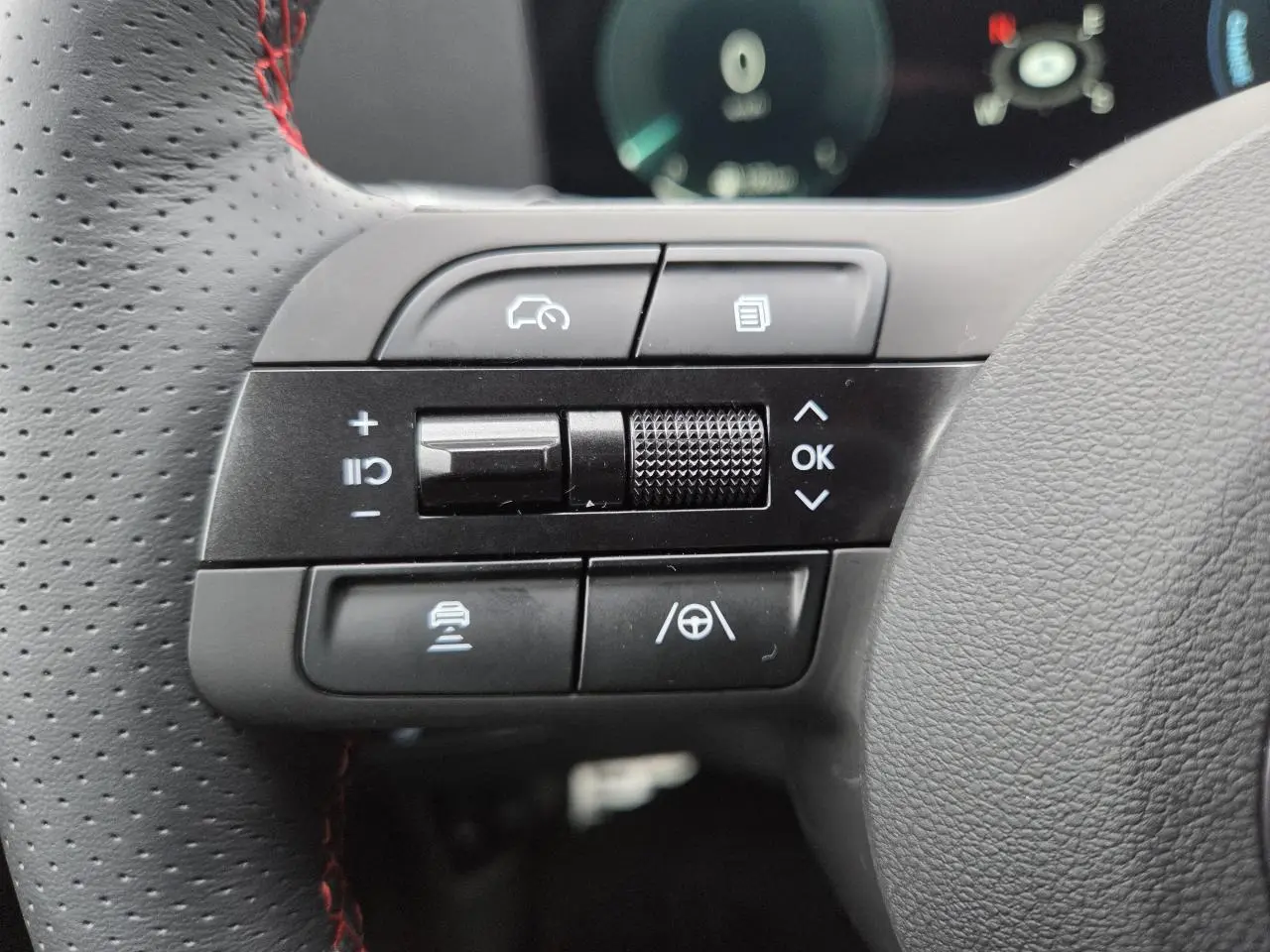 Gros plan sur les commandes gauche du volant cuir perforé avec surpiqûres rouges du Hyundai Tucson N Line gris métallisé.