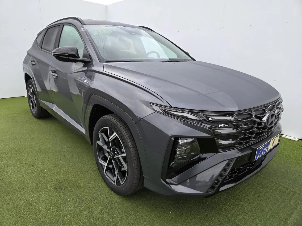 Hyundai Tucson 2025 gris métallisé en 3/4 avant droit avec calandre N Line et jantes alliage 19 pouces.